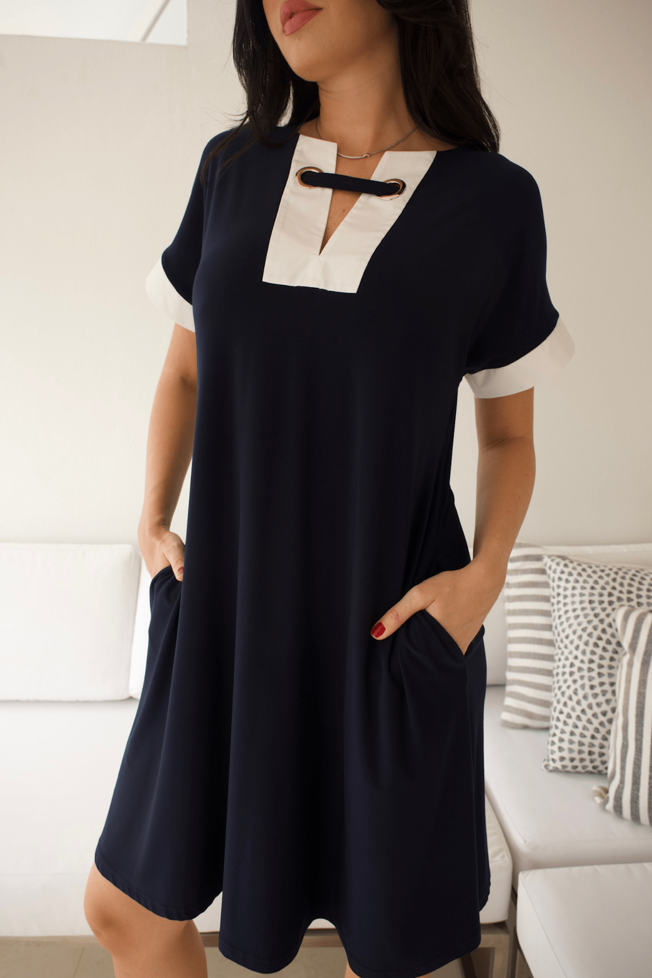 Detailed view of vanilla accents on the front of a navy blue dress, highlighting refined contrast and modern style.