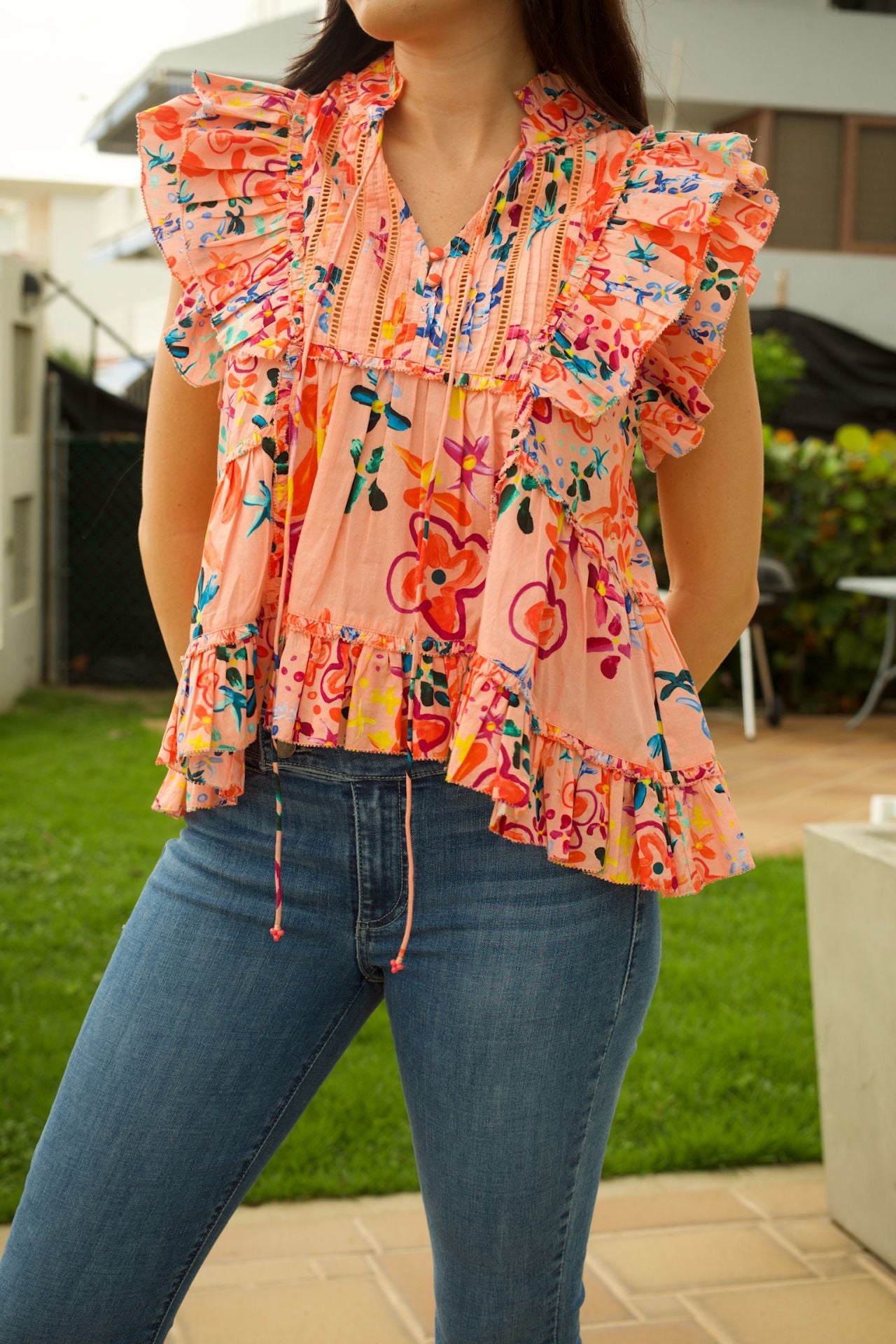 Close-up of the floral print on the women's ruffle high-low sleeveless top, highlighting the intricate burgundy, green, blue, and yellow pattern.