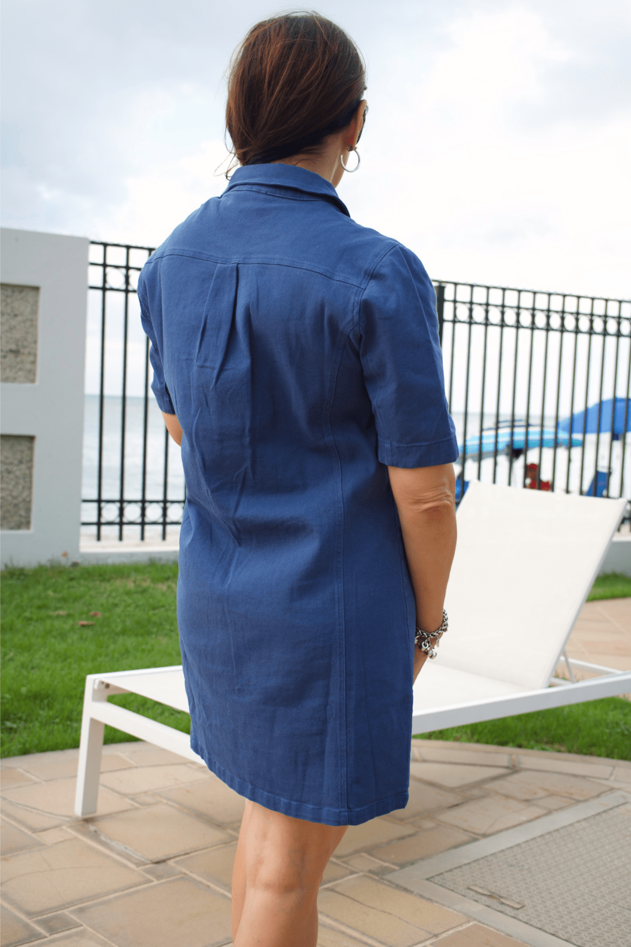 Back view of women's blue denim short dress with zipper front, offering a casual yet fashionable look.